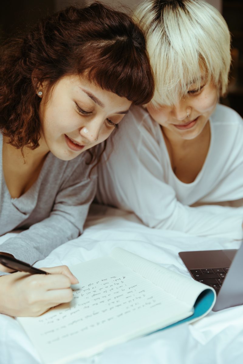 two women are writing on a piece of paper